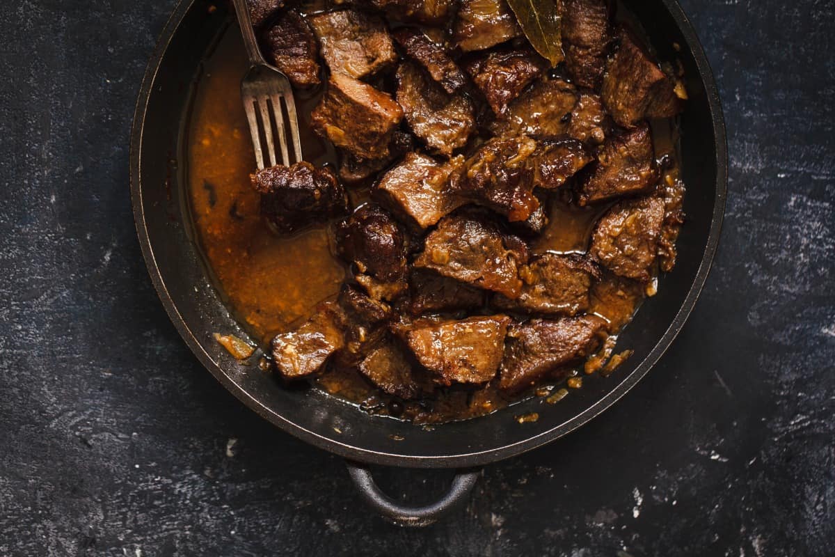 braised beef steak stew, overhead shot with a piece being lifted by a fork