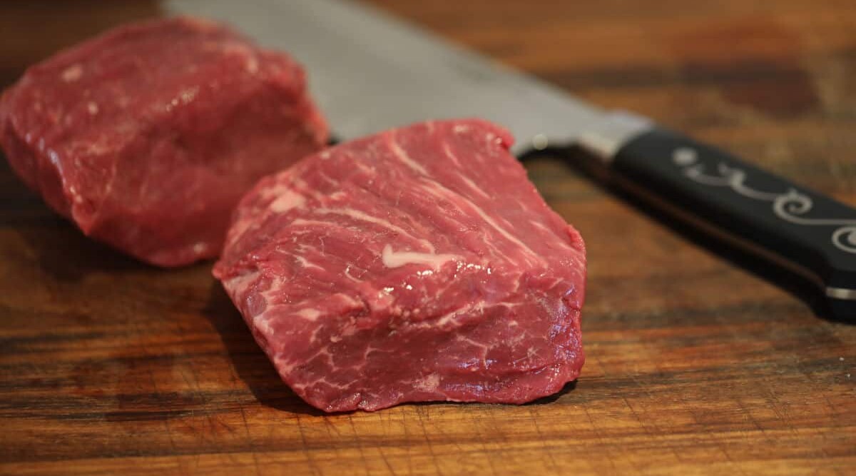 USDA graded fillet steak on a chopping board with a Japanese style knife.