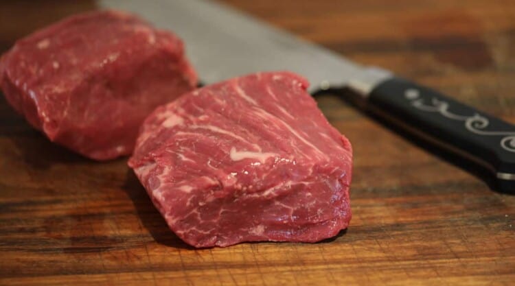 USDA graded fillet steak on a chopping board with a Japanese style knife.