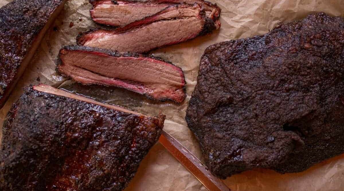 Close up of brisket with a deep BBQ bark, some of it sliced.