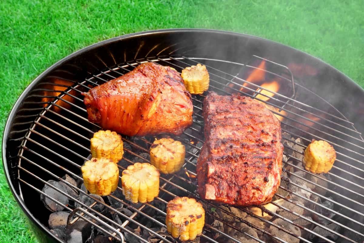 A charcoal grill with corn and ribs.