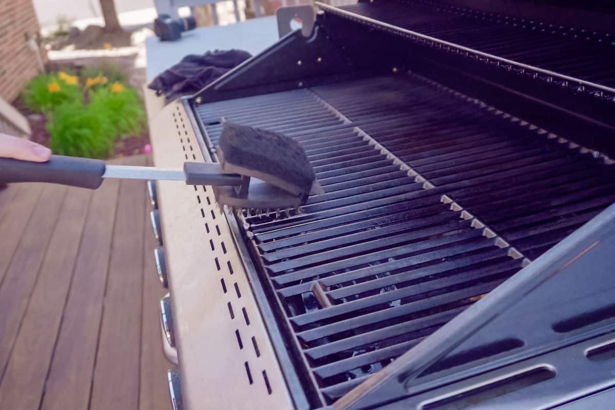 Brushing down grill grates to remove grease and grime.