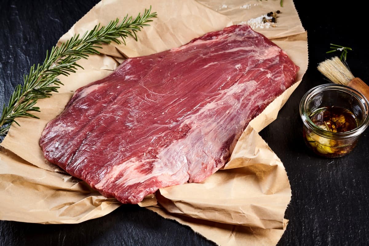 Raw flank on butcher paper, with a rosemary sprig