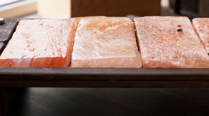 Close up of Himalayan slat blocks used for grilling, sitting in a charred wooden holder.