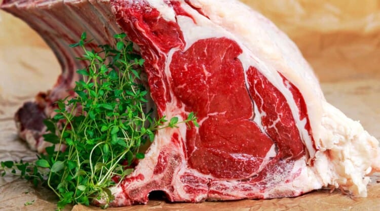 Prime rib on a chopping board with some thyme