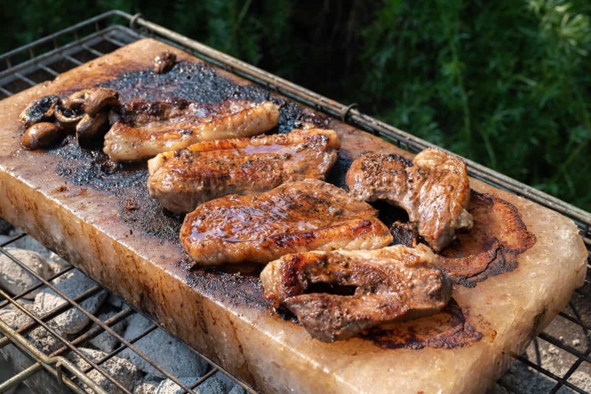 steak and mushroom being grilled on a salt bl.