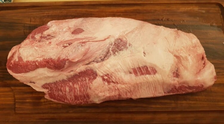 A full packer beef brisket on a wooden chopping board