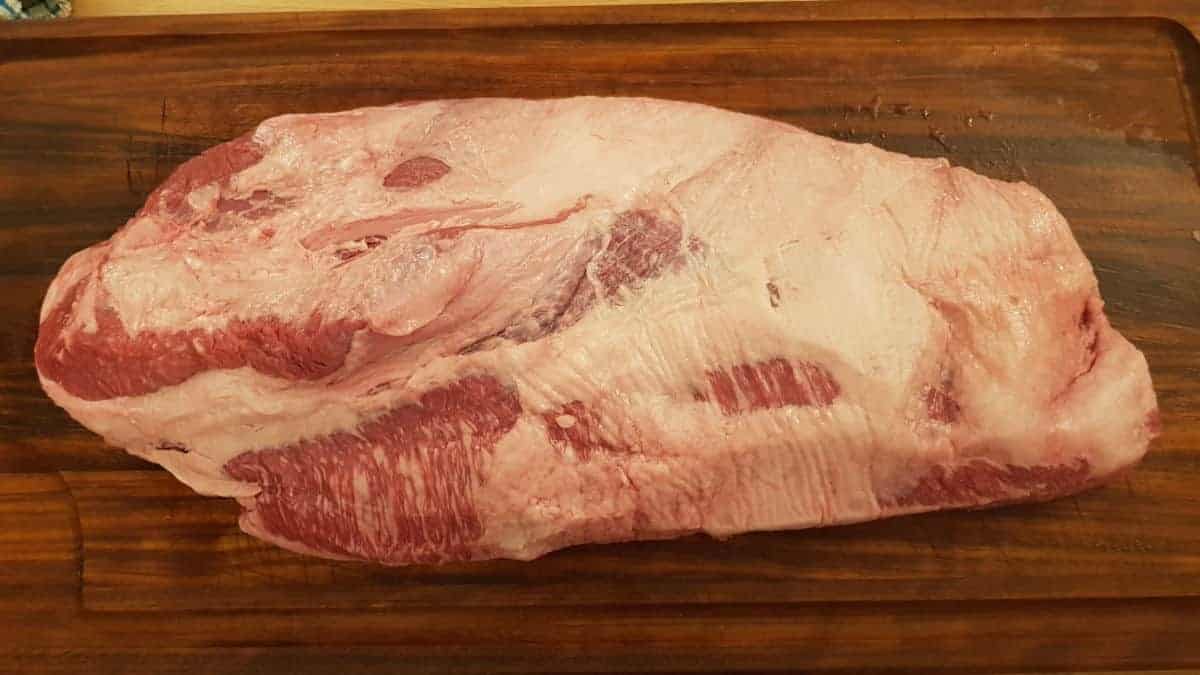 A full packer beef brisket on a wooden chopping board