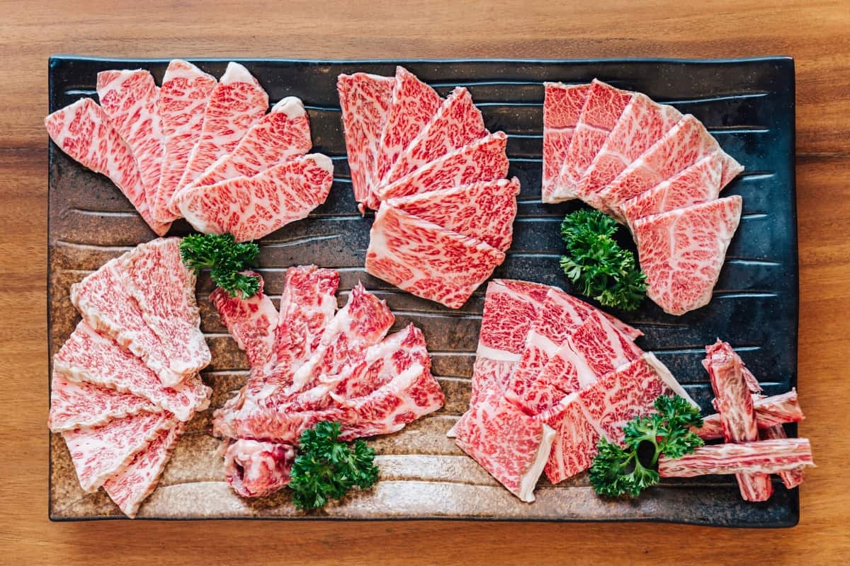 A selection of wagyu cuts spread out on a large cutting bo.