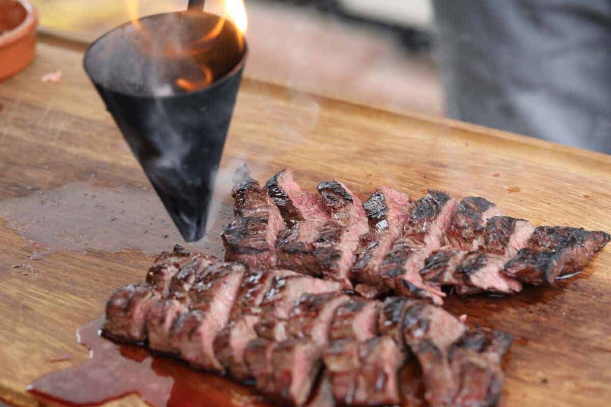 The flambadou dripping flaming bone marrow onto sliced hanger st.