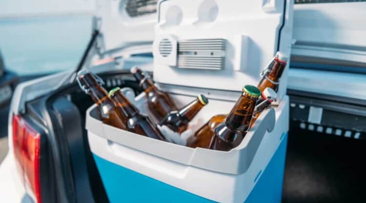 A cooler full of beers in the trunk of a car.