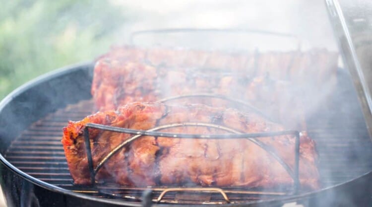 Racks of pork ribs cooking away in a BBQ smoker.