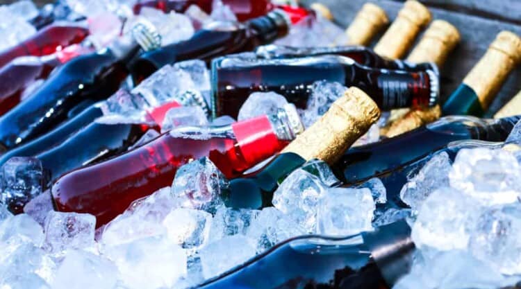 an assortment of bottles on ice in a wheeled cooler