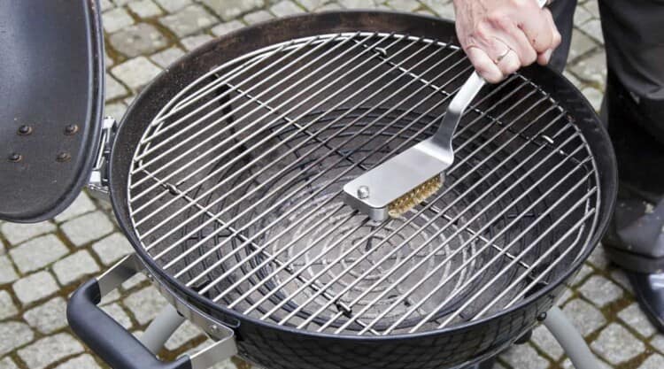 Cleaning a grills grates with a grill brush.