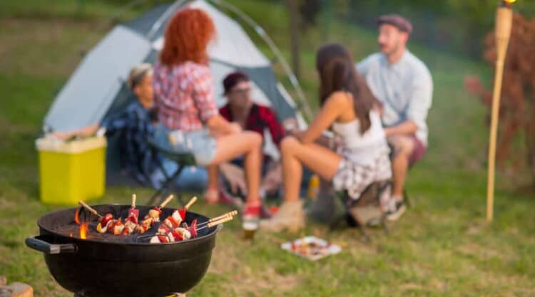 Close up of a camping grill, with a blurred background of a family camping