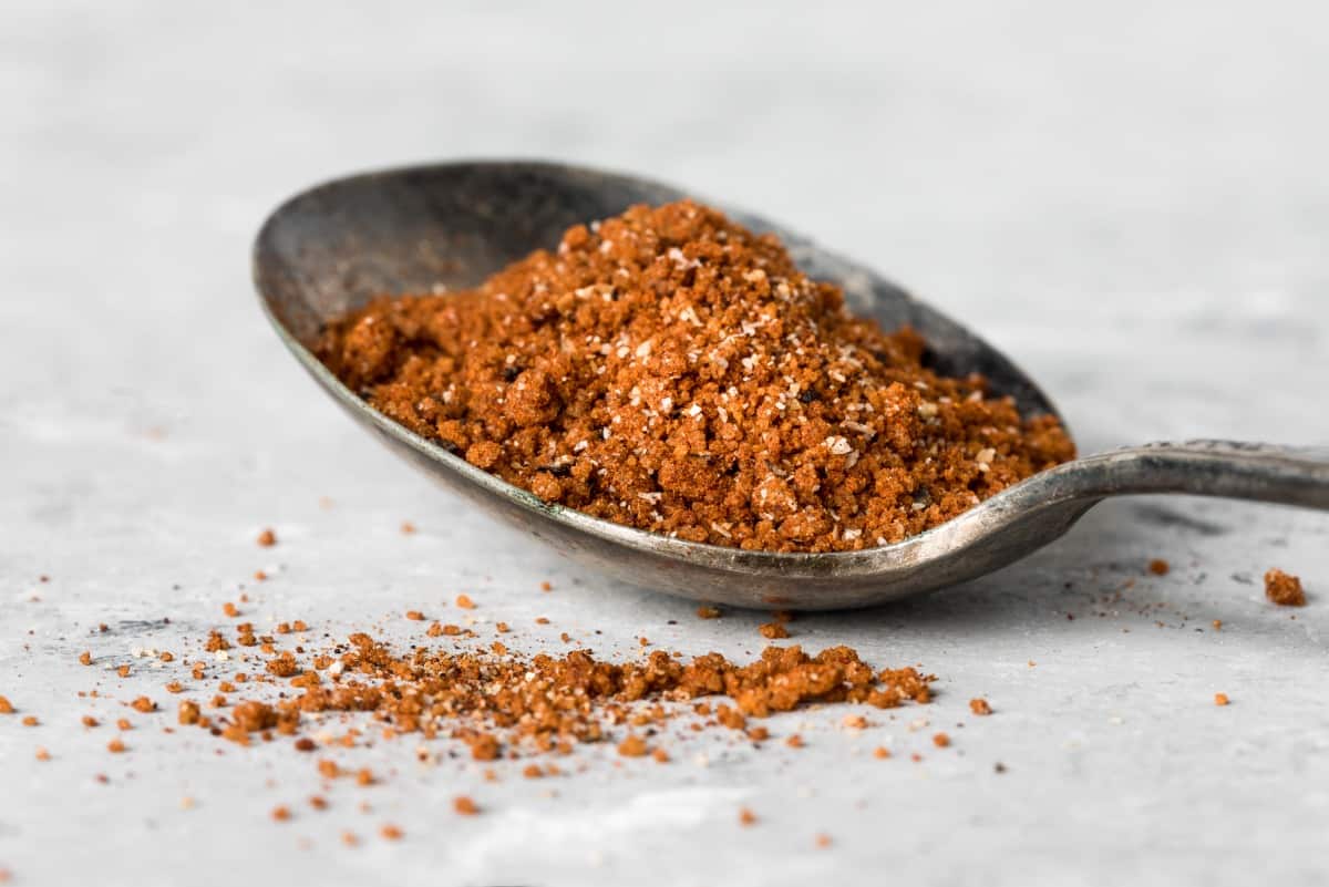A tablespoon of dry rub, on a white cloth, with a little spilling from the spoon