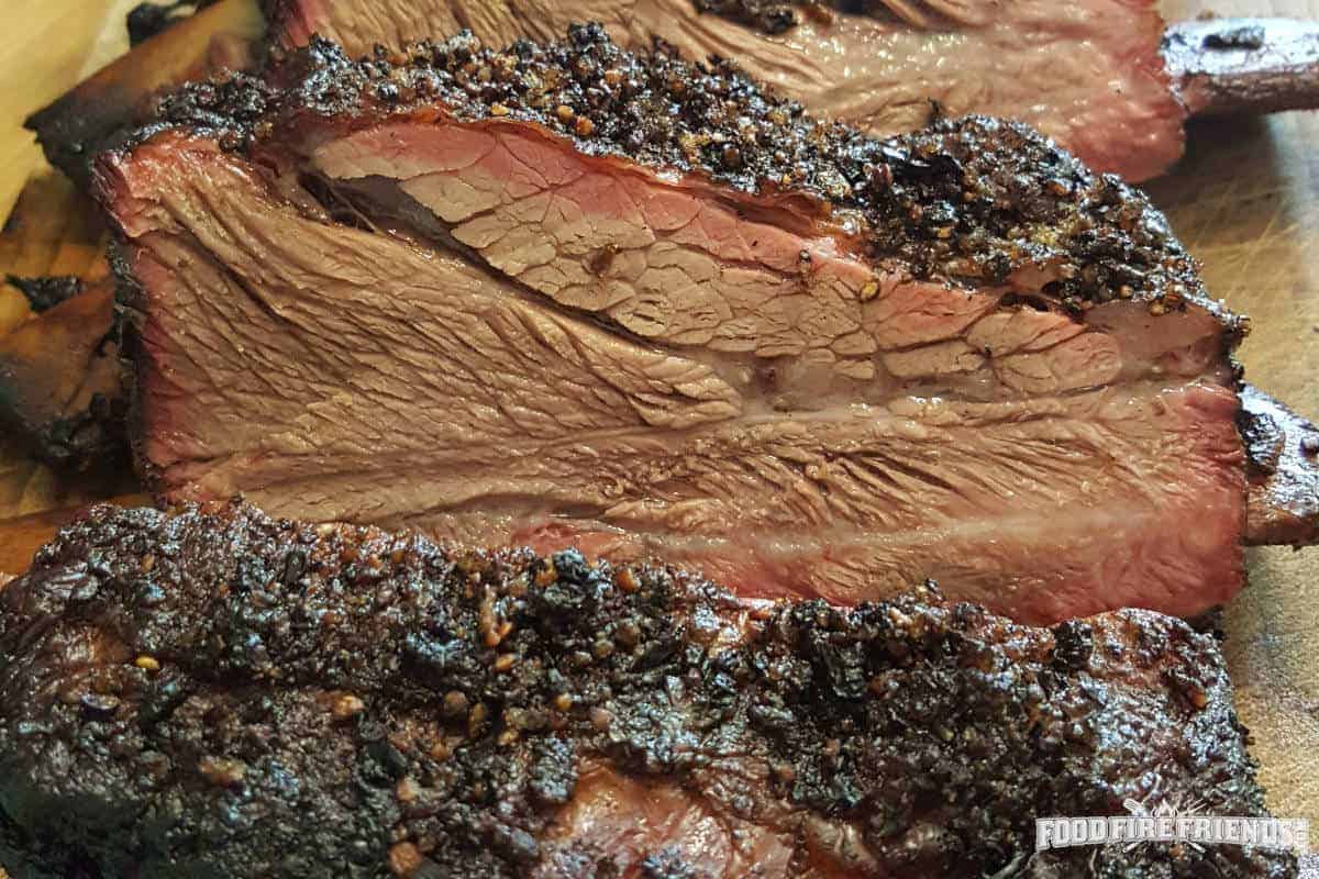 Close up of nice, moist beef ribs with a smoke ring and peppery rub crust.