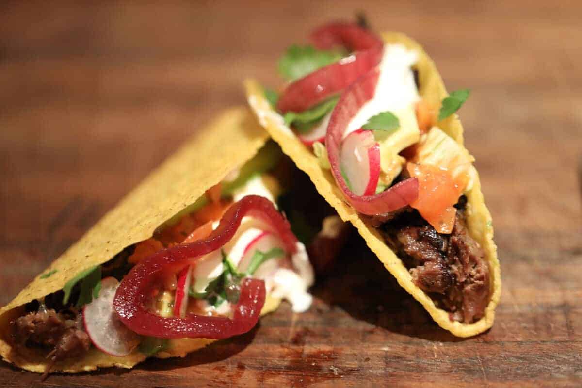 2 beef cheek tacos with onion, cheese, soured cream, corian.