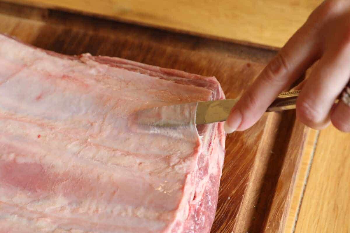 Inserting a blunt knife tip under the membrane on the back of beef ribs