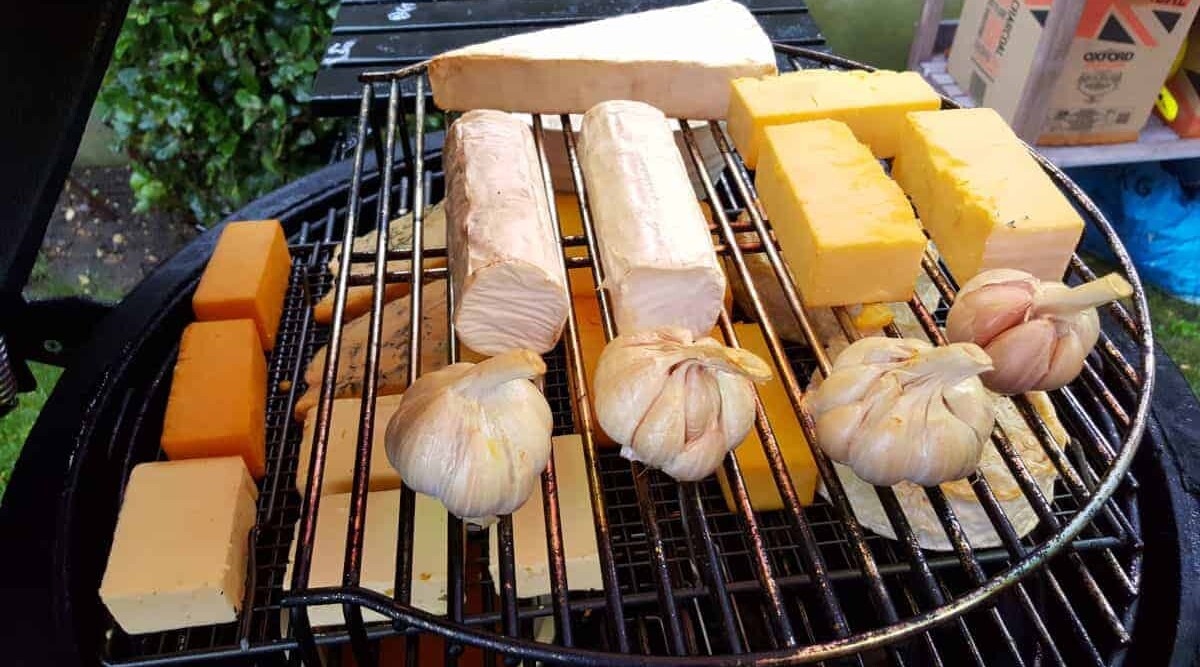 Cold smoke generator being used inside a kamado grill to smoke cheeses and garlic.