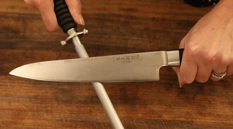 Womans hands honing a Japanese knife on a sharpening / honing steel.
