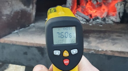 No touch infrared thermometer taking the temperature of a pizza oven.