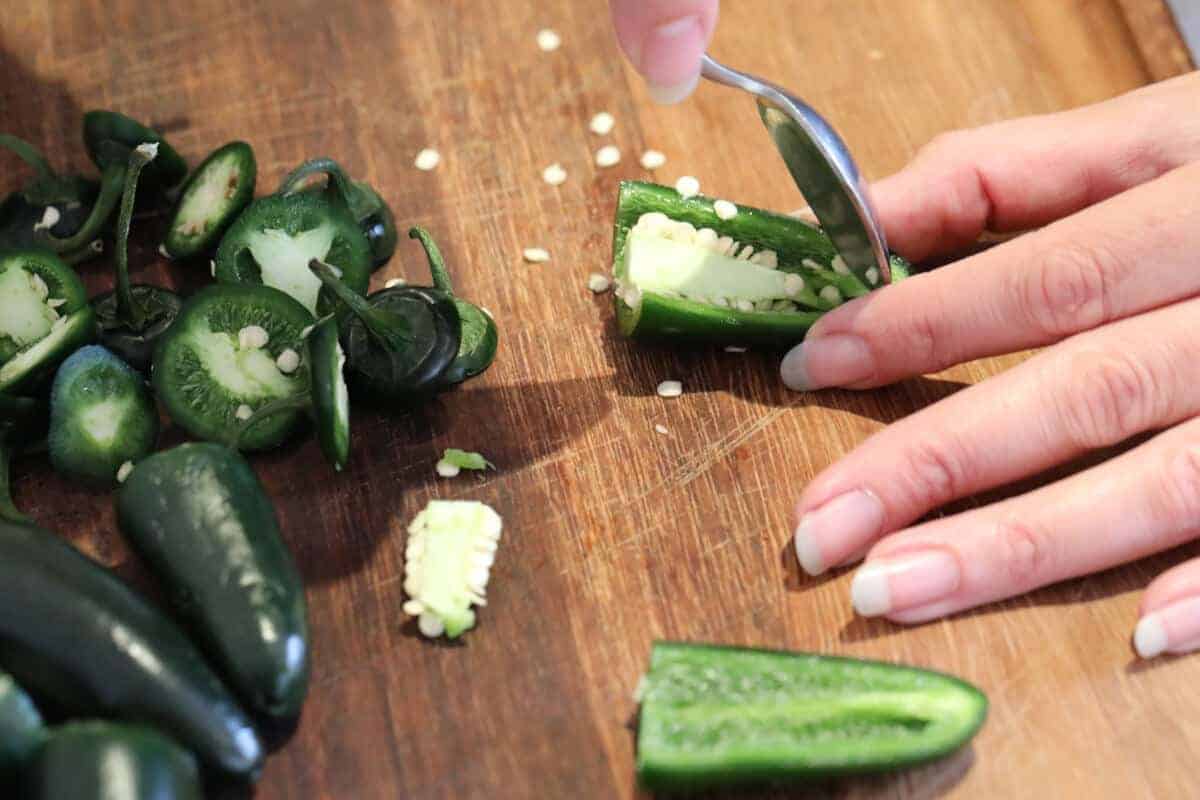 deseeding halved jalapeños with a teasp.