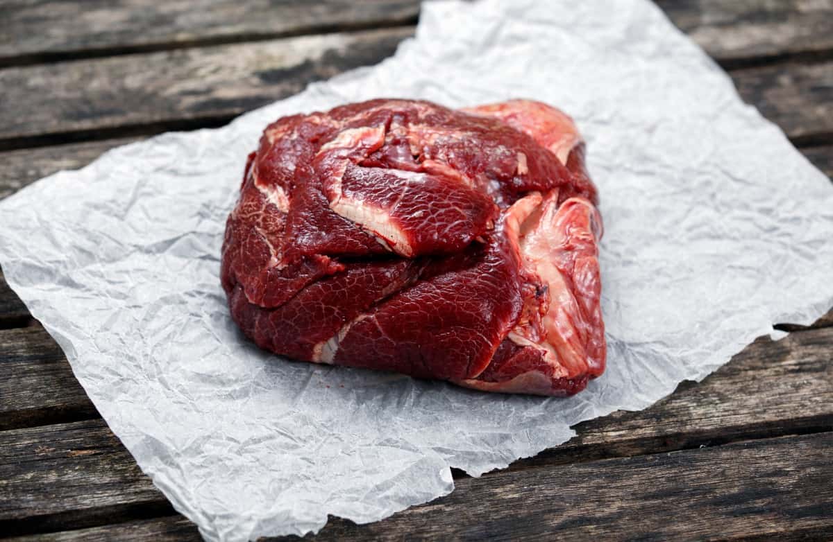 A raw ox cheek on white butcher pa.