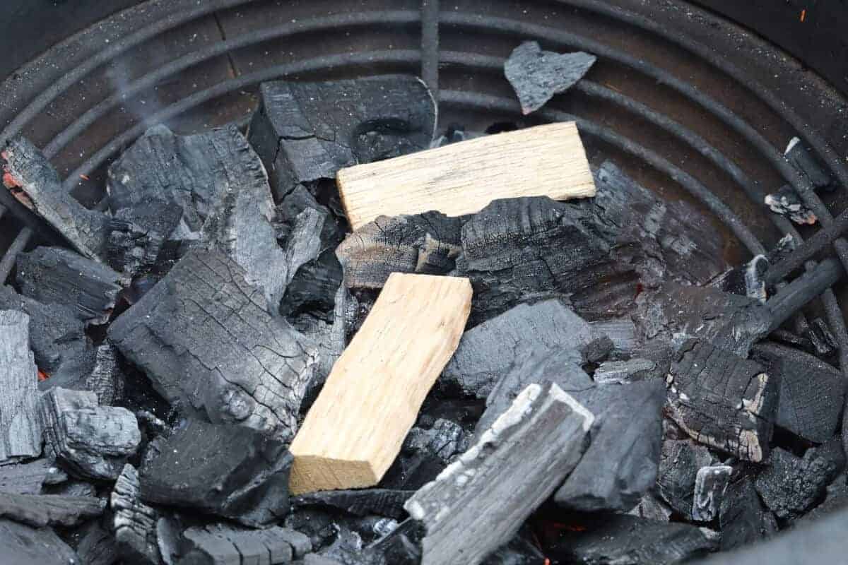 2 chunks of applewood atop smoldering lump charcoal in a Kamado .