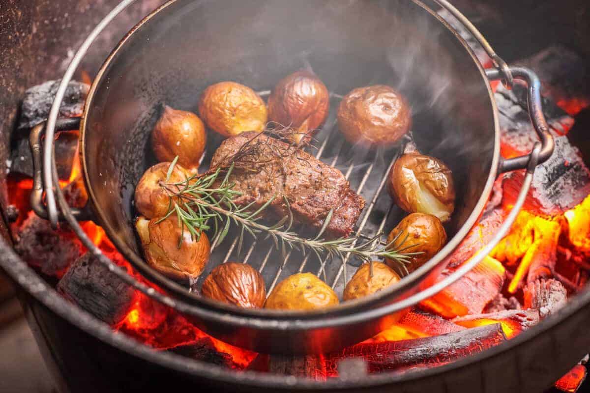 Beef, rosemary and roast potatoes in a Dutch oven on a gr.