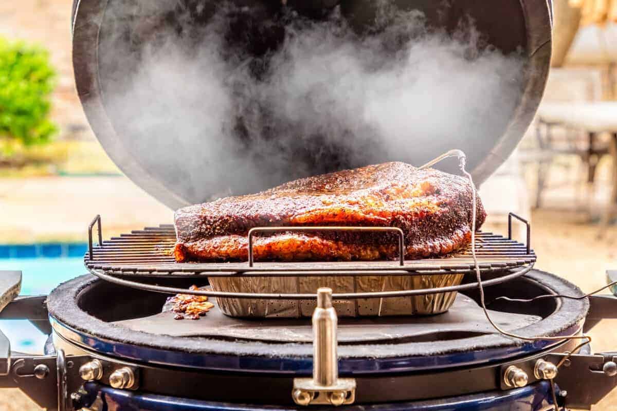 A brisket on a kamado grill over a water .