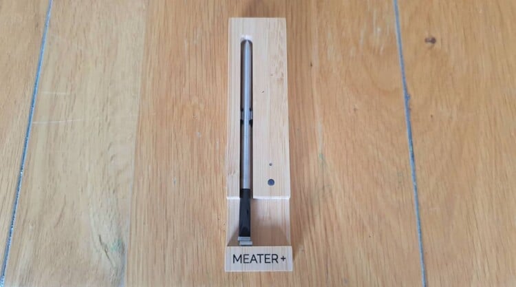 Meater+ thermometer in its charging block on a wooden table.