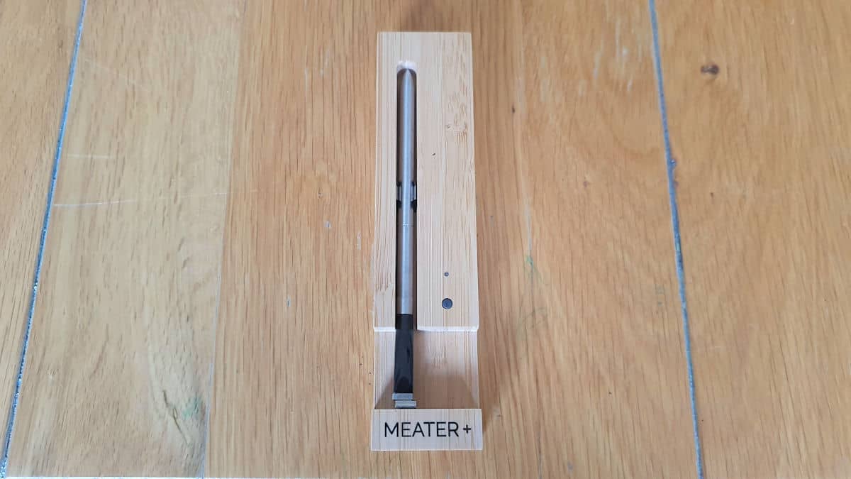 Meater+ thermometer in its charging block on a wooden table.
