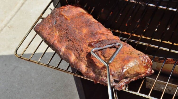 a rack of ribs being removed from an electric smoker.