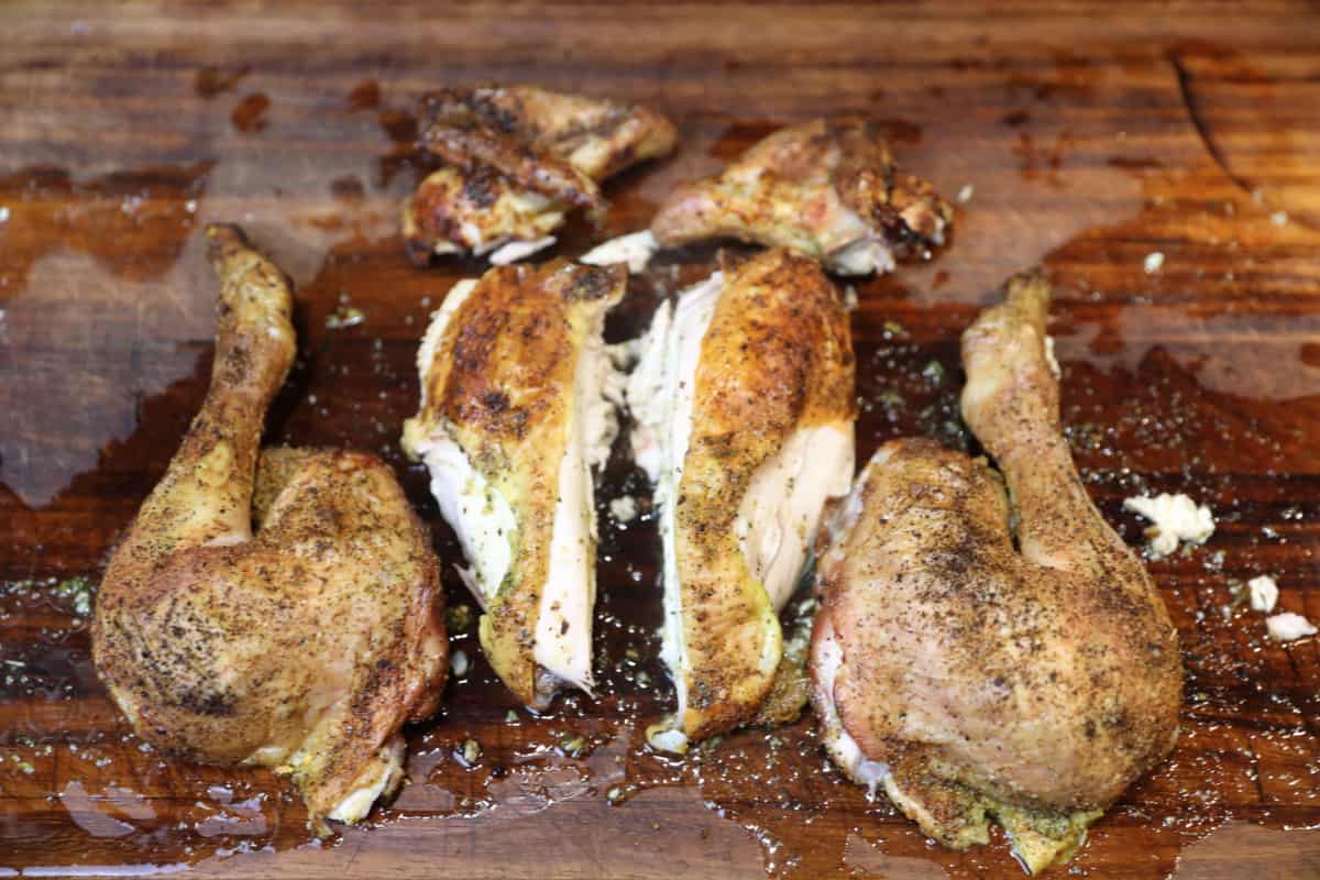 A quartered spatchcock chicken on a wooden cutting board