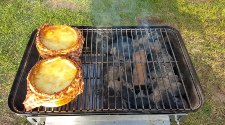 Two camembert cheeses being smoked on a weber go anywhere charcoal grill.