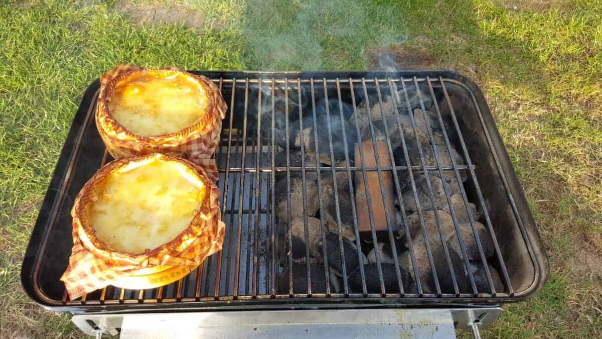 Two camembert cheeses being smoked on a weber go anywhere charcoal grill.