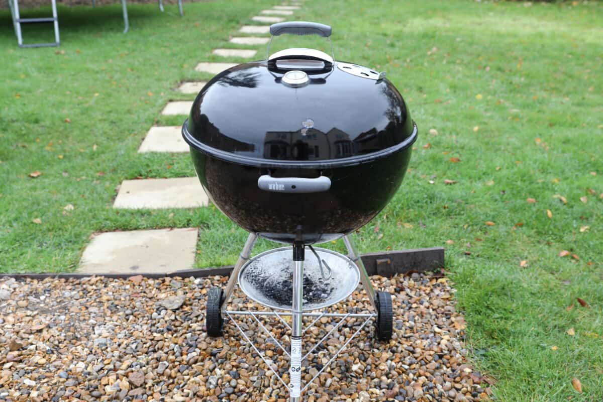 Weber kettle original grill on in my garden, sitting on a gravel path in front of grass.