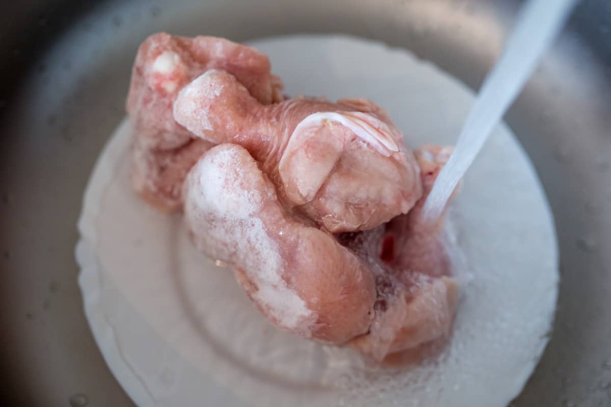 defrosting a plate of frozen chicken under hot water .