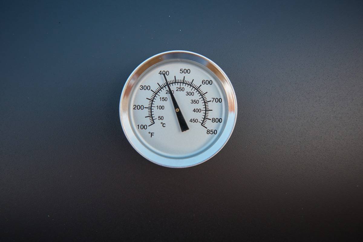 A grill lid thermometer with a black backgro.