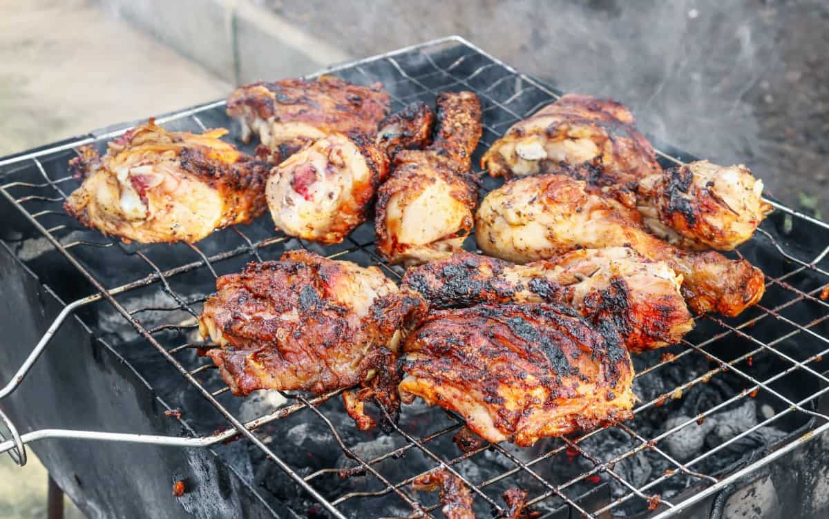 Grilling chicken thighs and drumsticks on an open charcoal grill