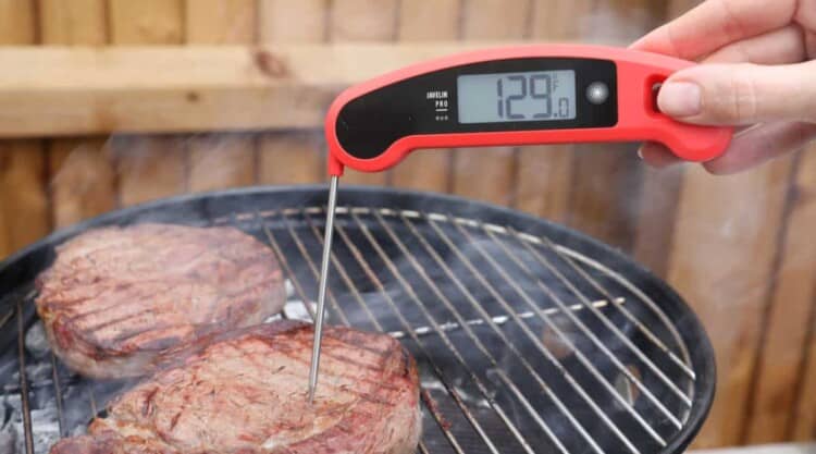 lavatools javelin pro instant read thermometer reading the temp of a steak on a grill.