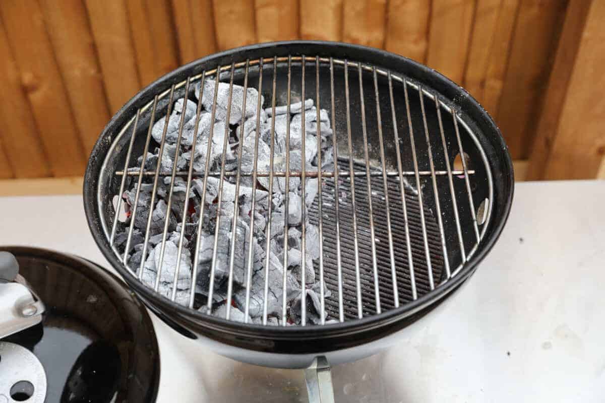 Weber smokey joe set up for two zone cooking with the grate in place.