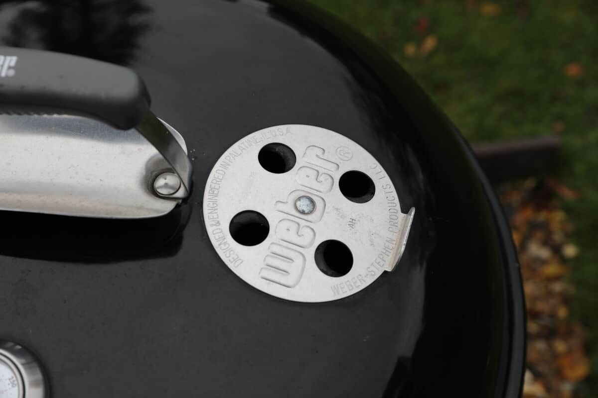 Close up of weber kettle top vent, handle and heat shield.