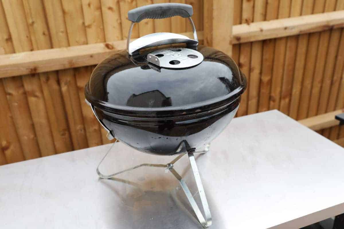 weber smokey joe on a stainless steel table.