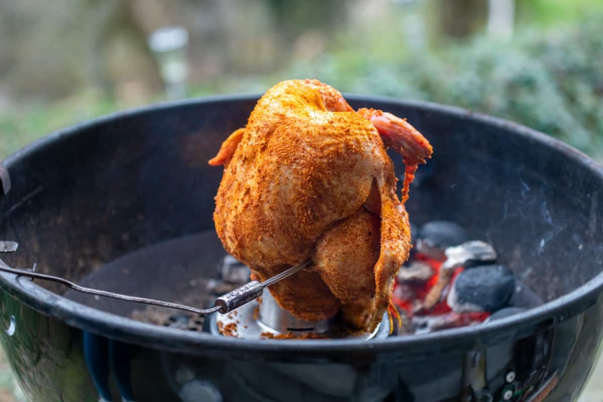 Whole chicken being grilled 'beer can style' on an open grill