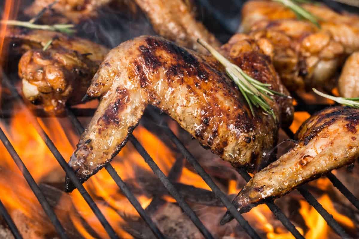 Grilling marinated chicken wings over an open flame