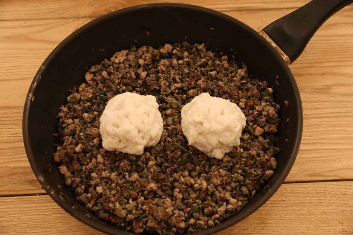 Two bread balls sitting on top of a pan full of sautéed porchetta stuff.