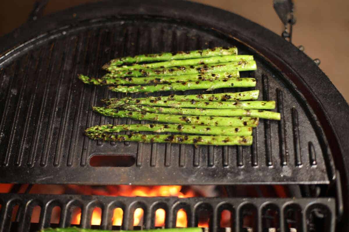 Asparagus on a solid cast iron grate on a charcoal gr.