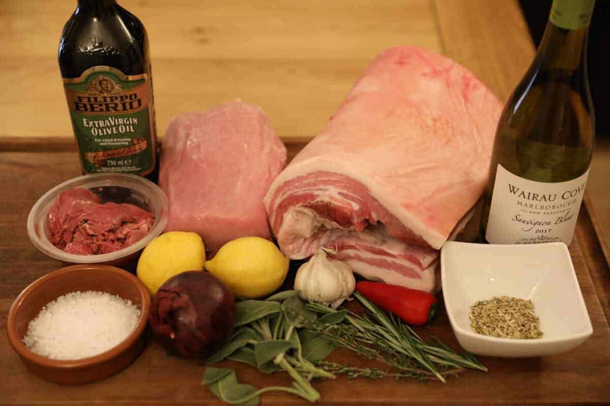 Ingredients for a porchetta laid out on a large wooden chopping board